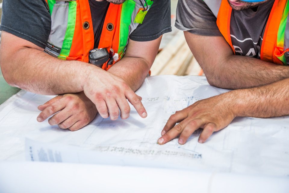Dos técnicos revisando y señalando un plano de obra